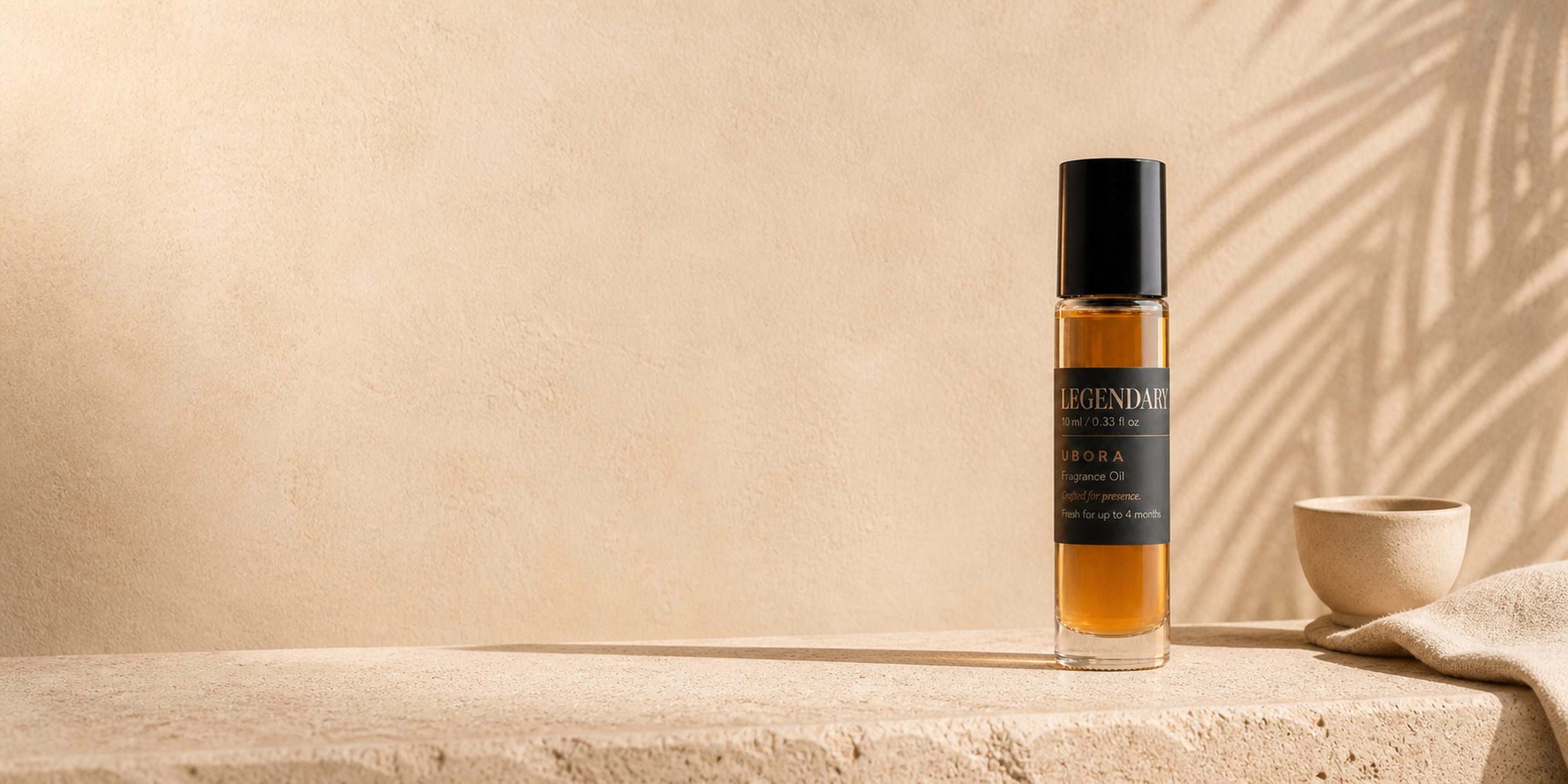 UBORA Legendary fragrance oil on a sunlit plaster ledge.