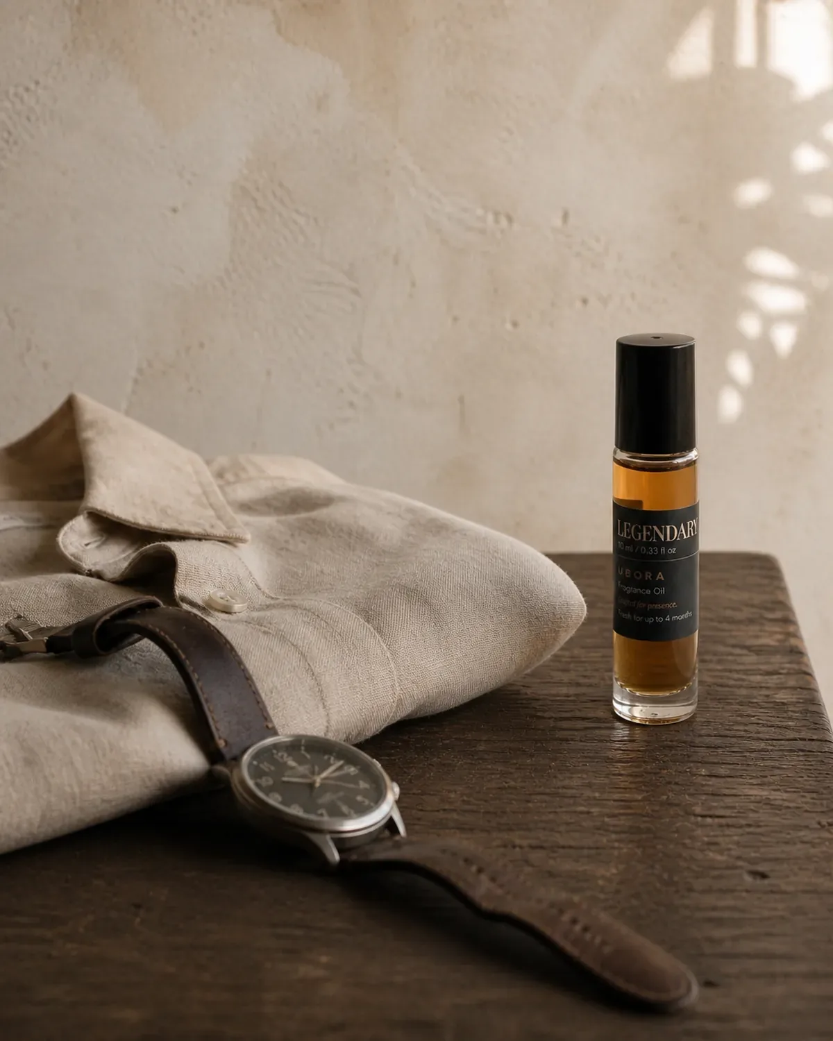 UBORA fragrance oil beside a linen shirt and watch