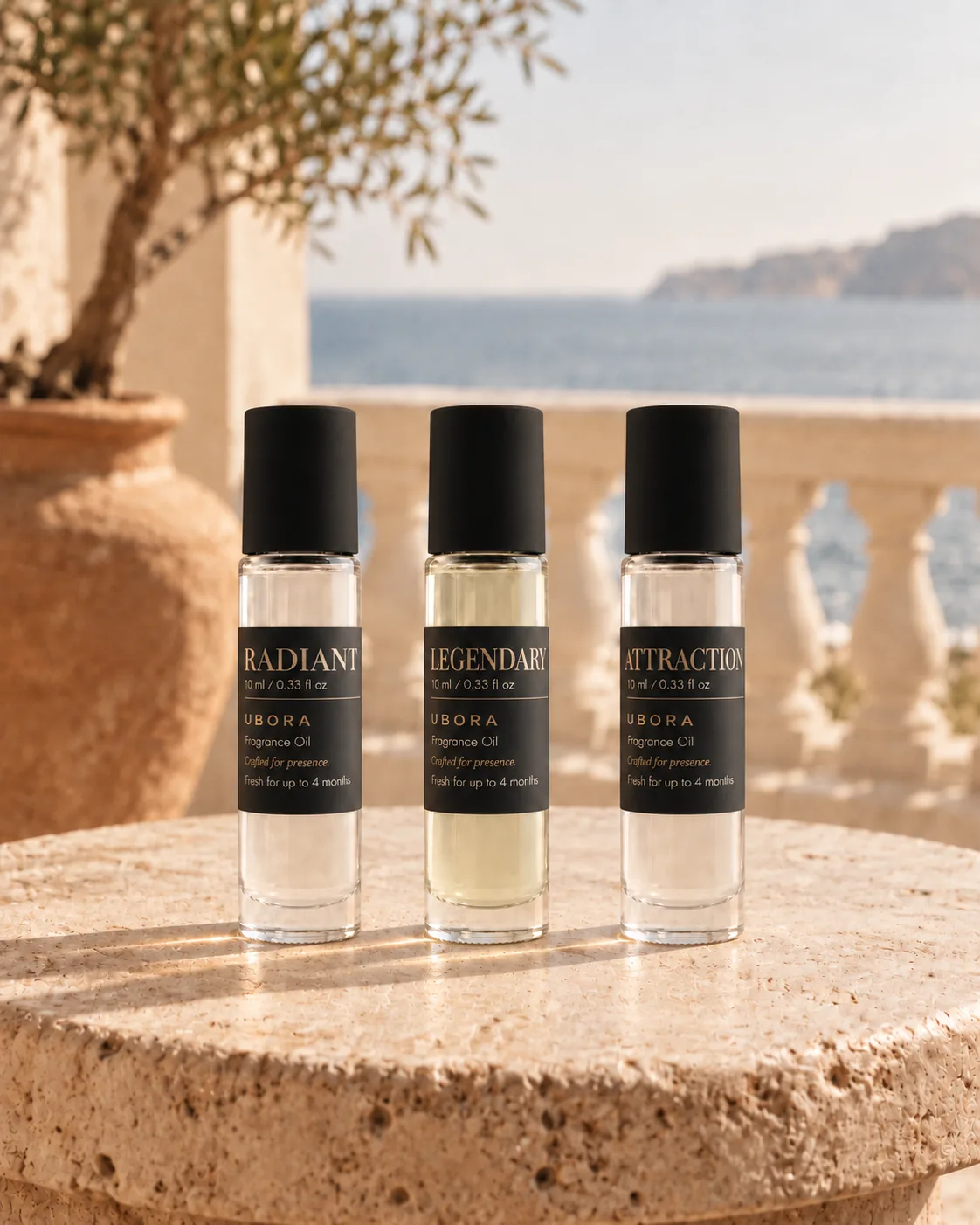 Three UBORA fragrance oils, Radiant, Legendary and Attraction, on a stone table by the sea
